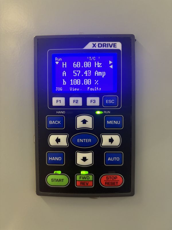 X-Drive keypad on the cabinet door with a blue display reading Run, 60.00 Hz, 57.48 Amp, 100 percent