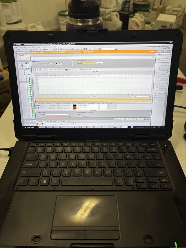 Rugged laptop on a pump house bench showing a pressure trend in the Siemens programming software